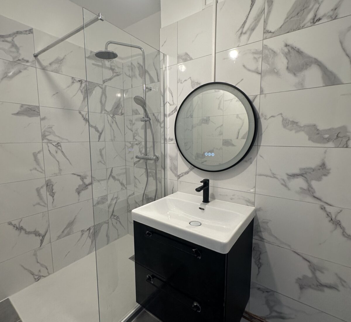 Salle d’eau rénovée : douche à l’italienne, faïence effet marbre et meuble vasque noir